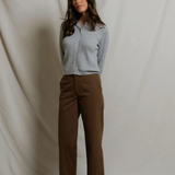 woman in grey cardigan and brown pants on draped background 