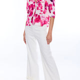 woman in blurred floral blouse and white wide leg pants on white background 