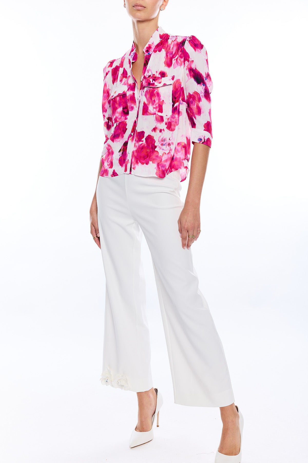 woman in blurred floral blouse and white wide leg pants on white background 