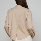 Woman wearing a beige ribbed blouse against a plain background