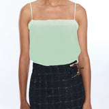Woman wearing a light green strapless top and black plaid skirt on a white background