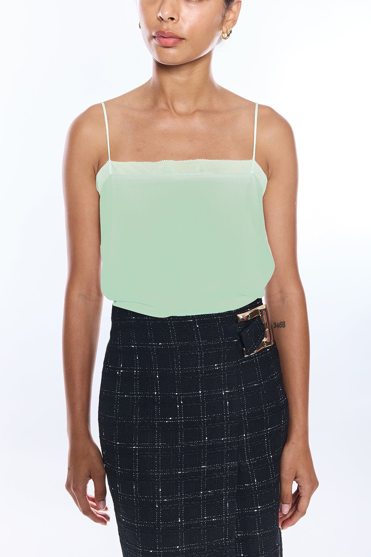 Woman wearing a light green strapless top and black plaid skirt on a white background