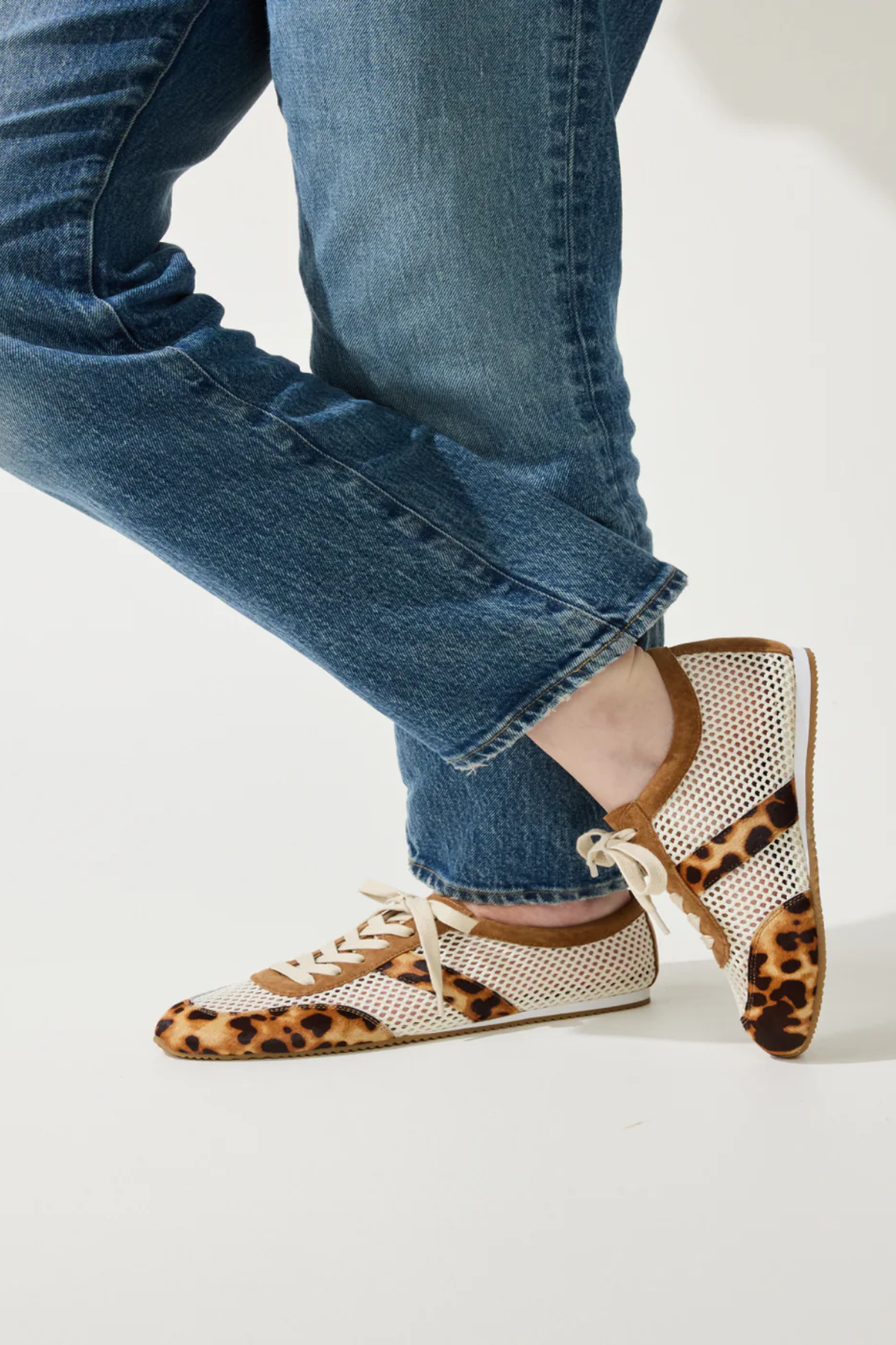 person wearing leopard and mesh sneakers on white background 