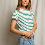 Woman wearing a green and white striped shirt and blue jeans against a plain background