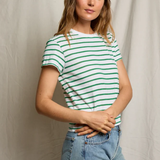Woman wearing a green and white striped shirt and blue jeans against a plain background