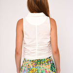 Woman wearing a white sleeveless top and colorful floral skirt on a plain background