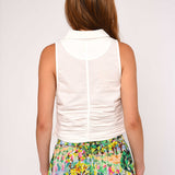 Woman wearing a white sleeveless top and colorful floral skirt on a plain background