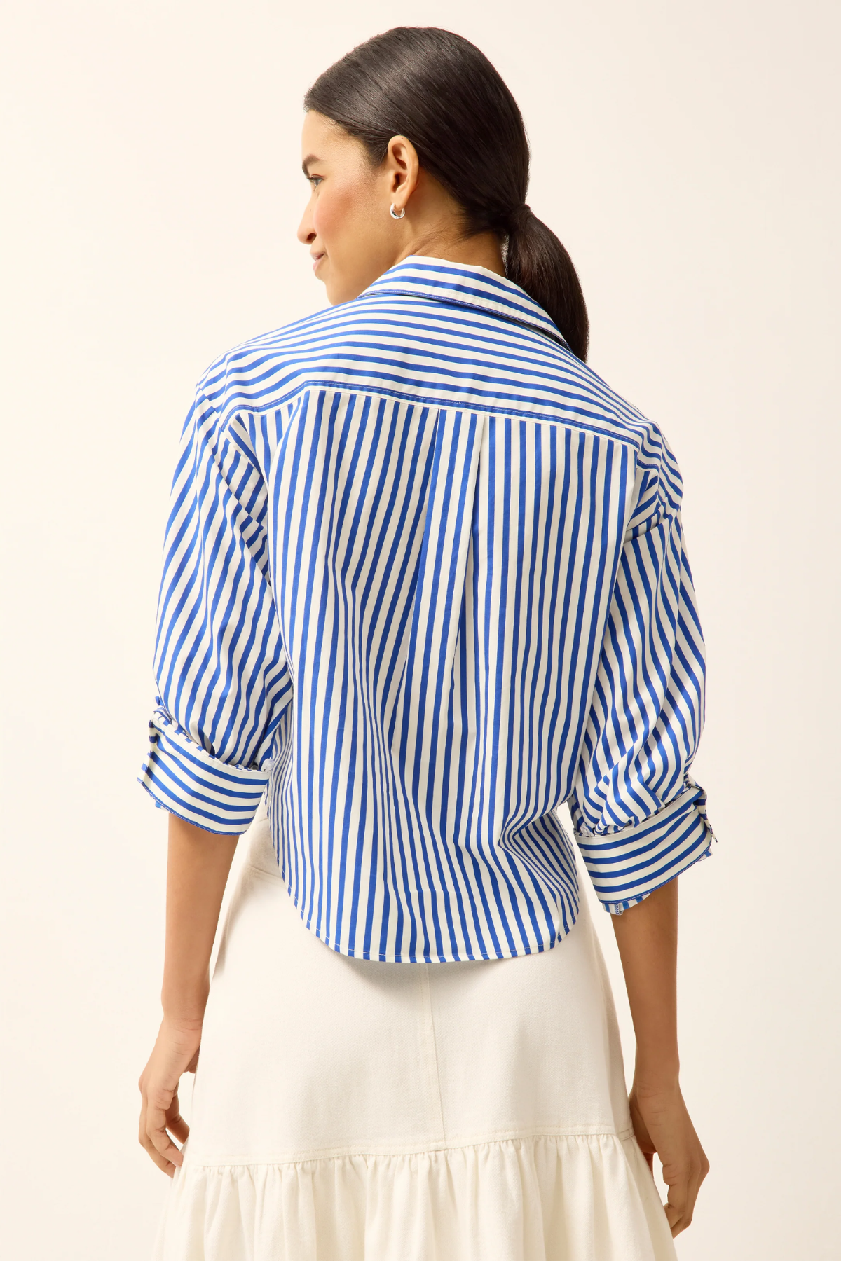Woman wearing a blue and white striped shirt with a beige background