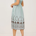 Woman wearing a light blue dress with lace details on a white background