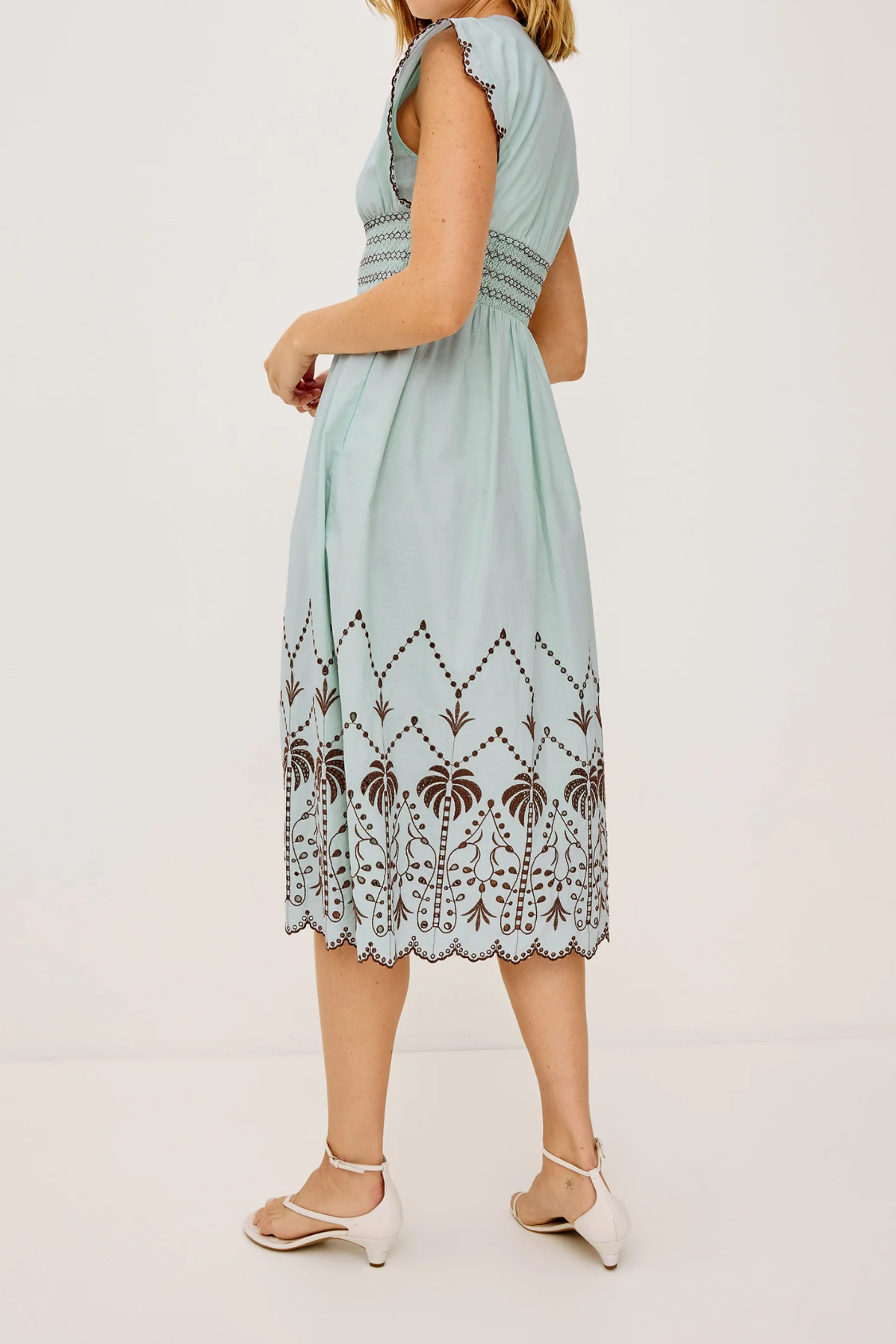 Woman wearing a light blue dress with lace details on a white background