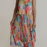 Woman wearing a colorful patterned dress against a plain background