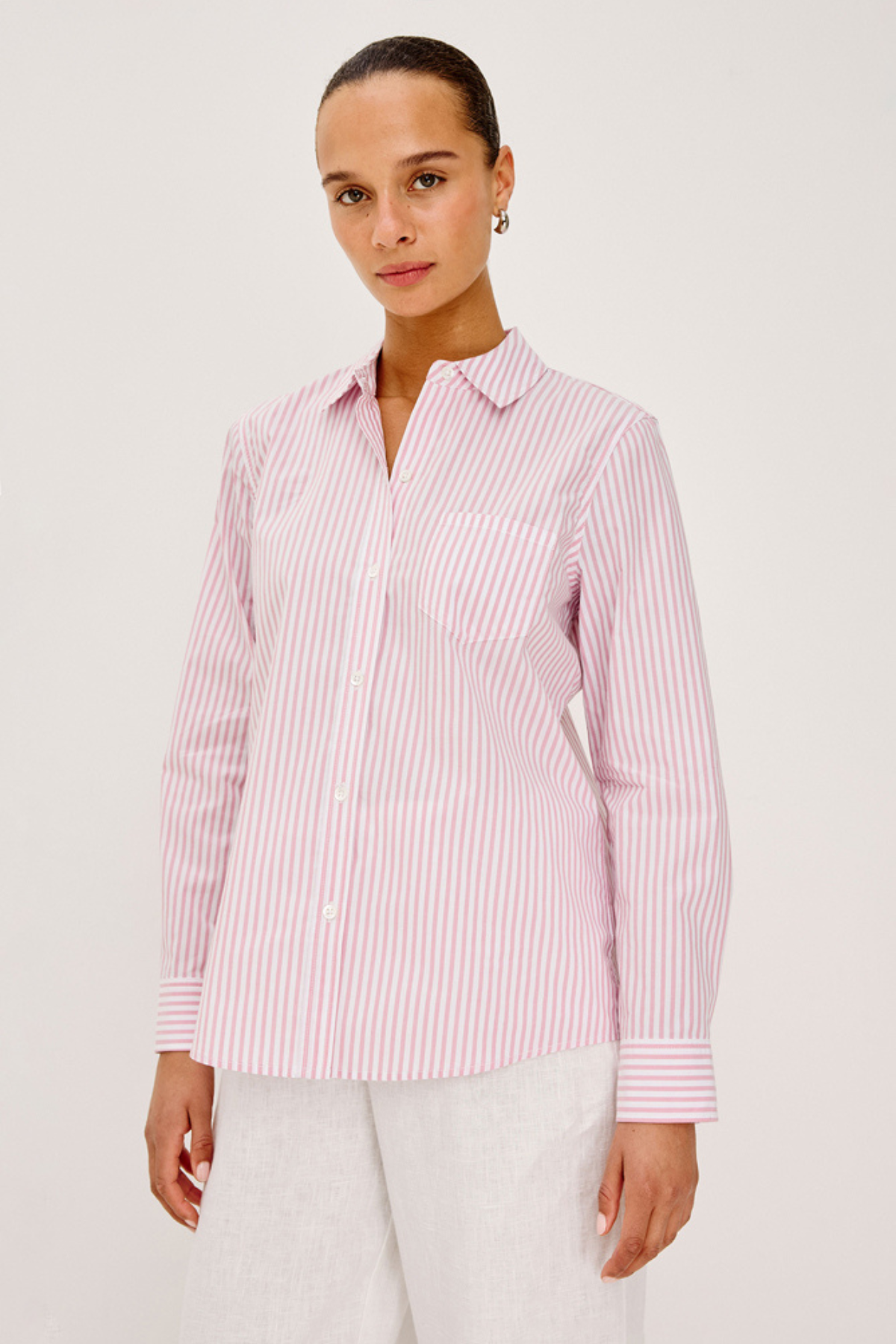 woman in pink and white stripe button down on white background 