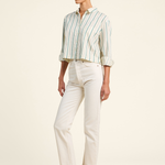 Woman wearing a striped shirt and white pants on a plain background