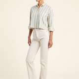 Woman wearing a striped shirt and white pants on a plain background