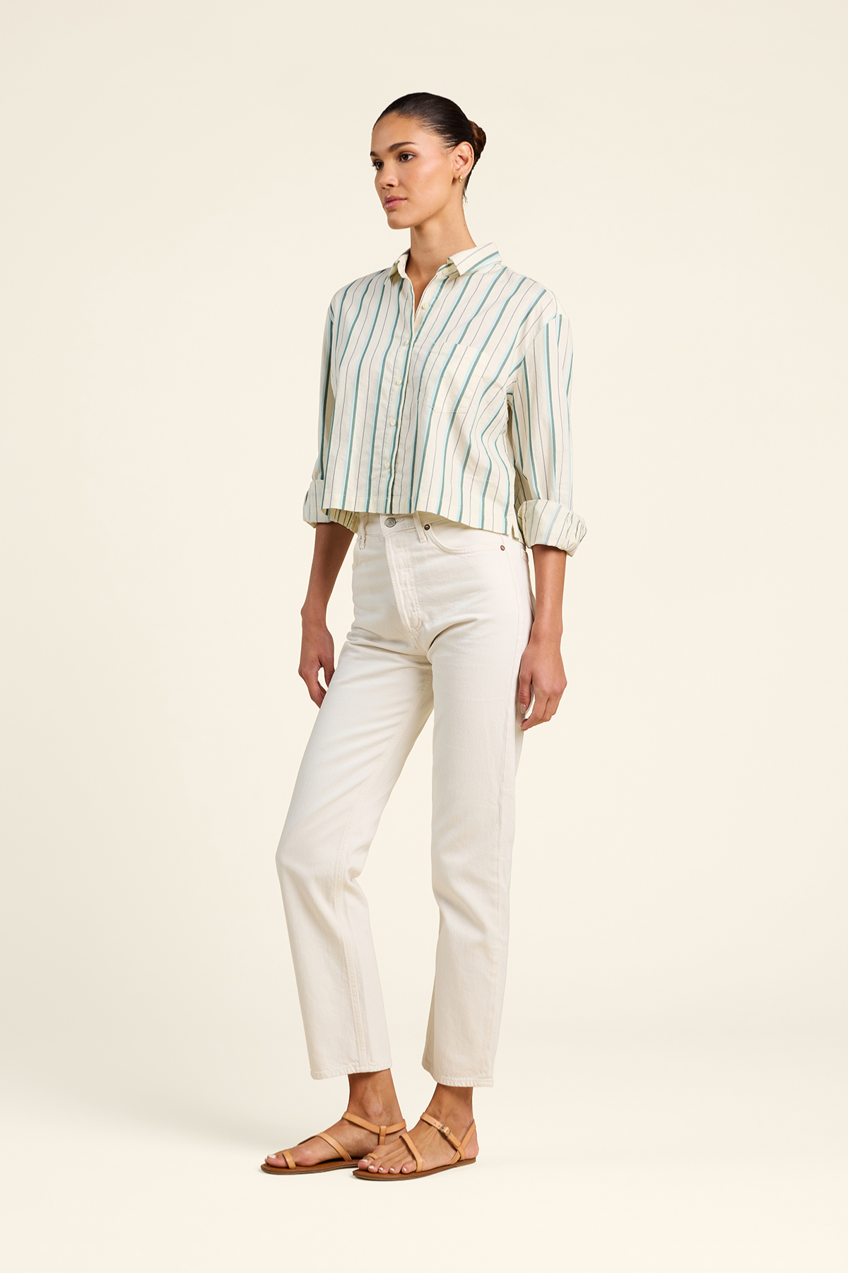 Woman wearing a striped shirt and white pants on a plain background