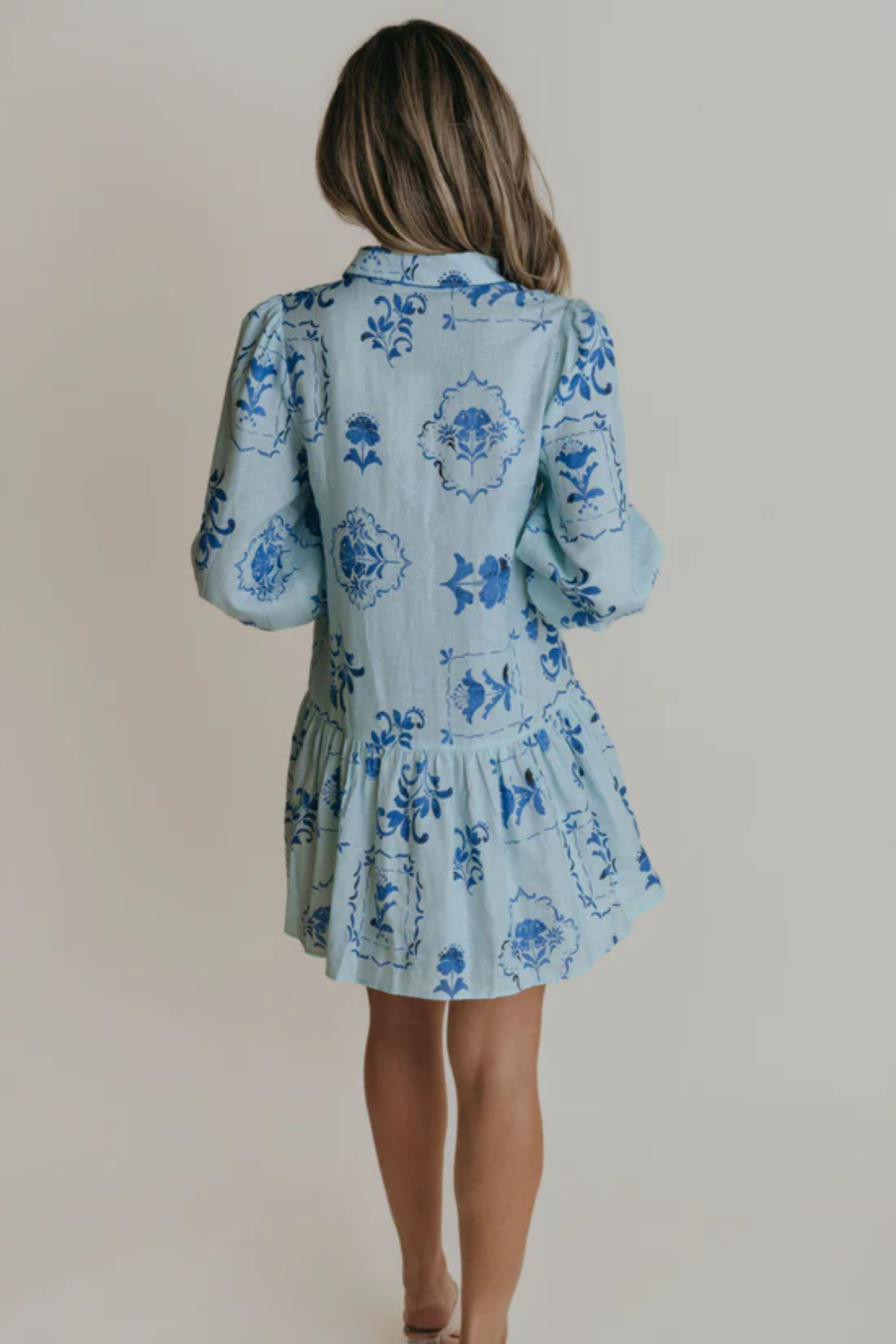 Woman wearing a blue floral dress against a plain background