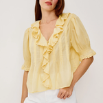 Woman wearing a yellow blouse with ruffles on a white background
