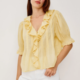 Woman wearing a yellow blouse with ruffles on a white background