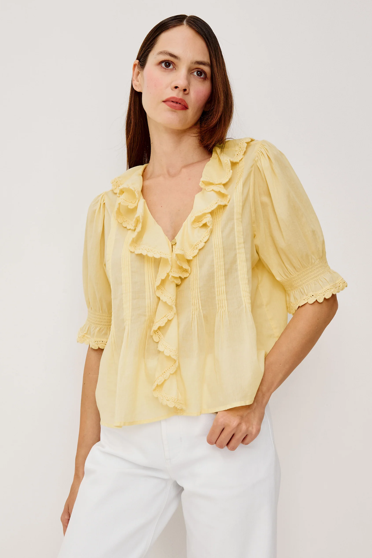 Woman wearing a yellow blouse with ruffles on a white background