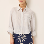 Woman wearing a striped shirt and navy skirt with white patterns against a beige background