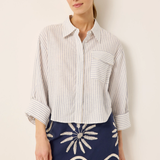 Woman wearing a striped shirt and navy skirt with white patterns against a beige background