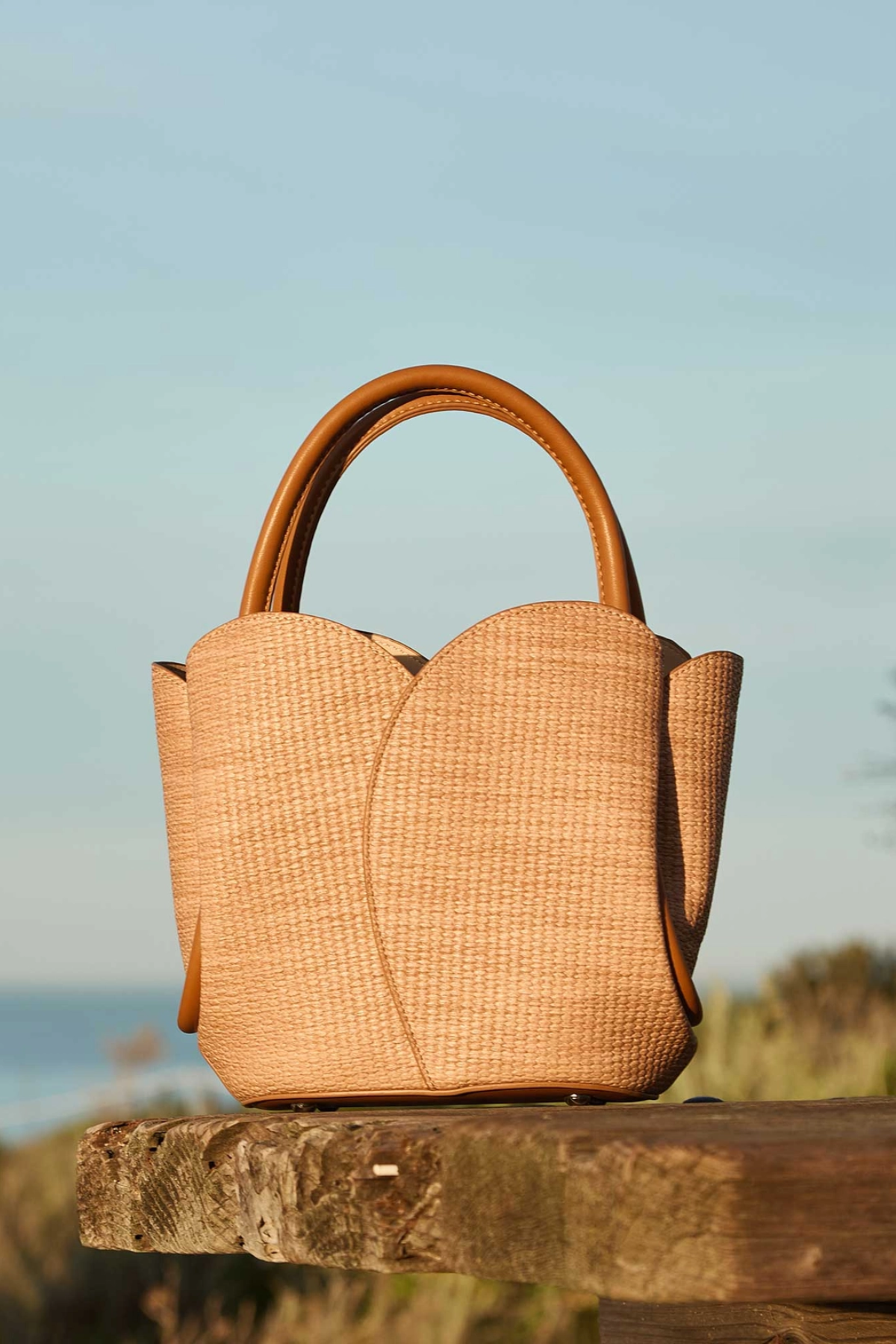 Woven handbag on a wooden surface with a blurred natural background