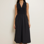 Woman wearing a black sleeveless dress against a plain background
