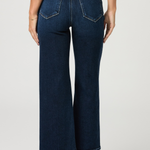 Person wearing dark blue wide-leg jeans on a plain background