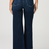 Person wearing dark blue wide-leg jeans on a plain background