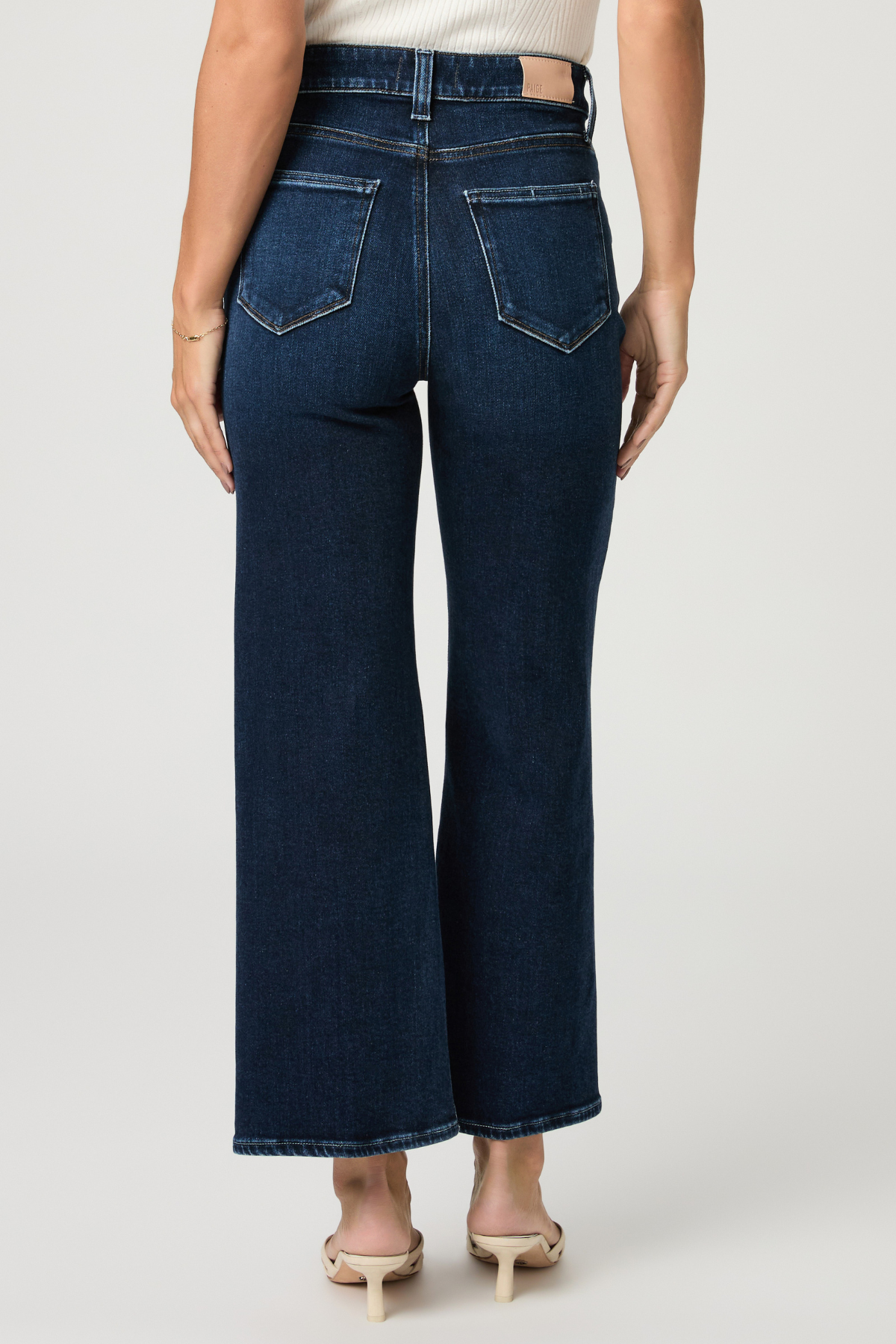 Person wearing dark blue wide-leg jeans on a plain background