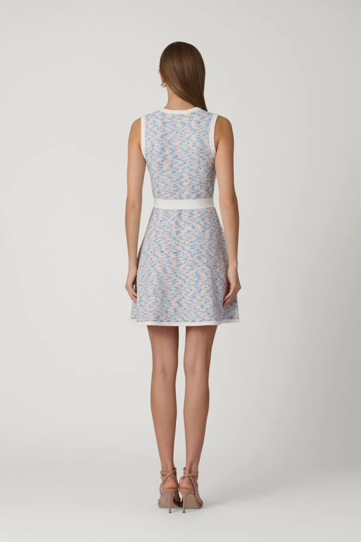 back of woman in multicolored dress on white background 