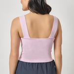 Woman wearing a light pink top and dark gray skirt on a white background