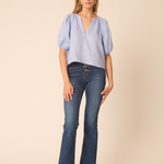 woman in blue top and denim on tan background 