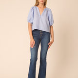 woman in blue top and denim on tan background 