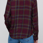 A person shown from the back wearing a long-sleeve plaid button-up shirt in deep burgundy with yellow, blue, and green stripes, paired with blue jeans, against a solid gray background.