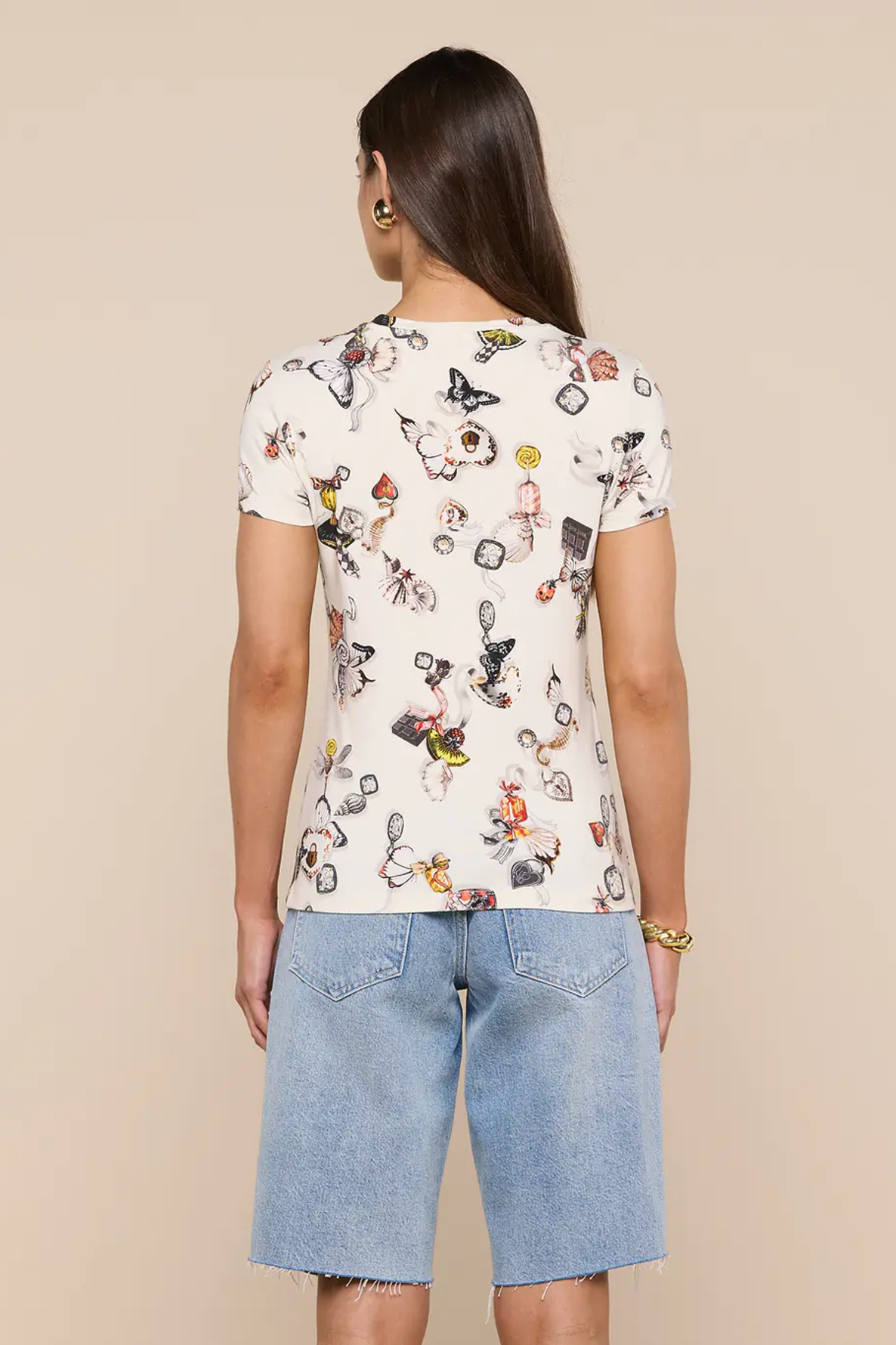 Person wearing a white t-shirt with cartoon character print and denim shorts on a beige background