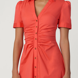Woman wearing a coral dress with short sleeves on a white background