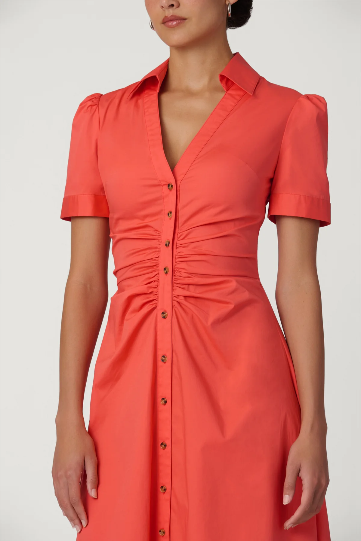 Woman wearing a coral dress with short sleeves on a white background