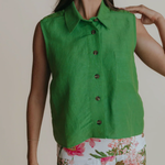 Woman wearing a green sleeveless shirt with a floral skirt against a neutral background