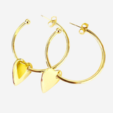 A pair of gold hoop earrings with dangling polished heart charms, displayed on a clean, light gray background.