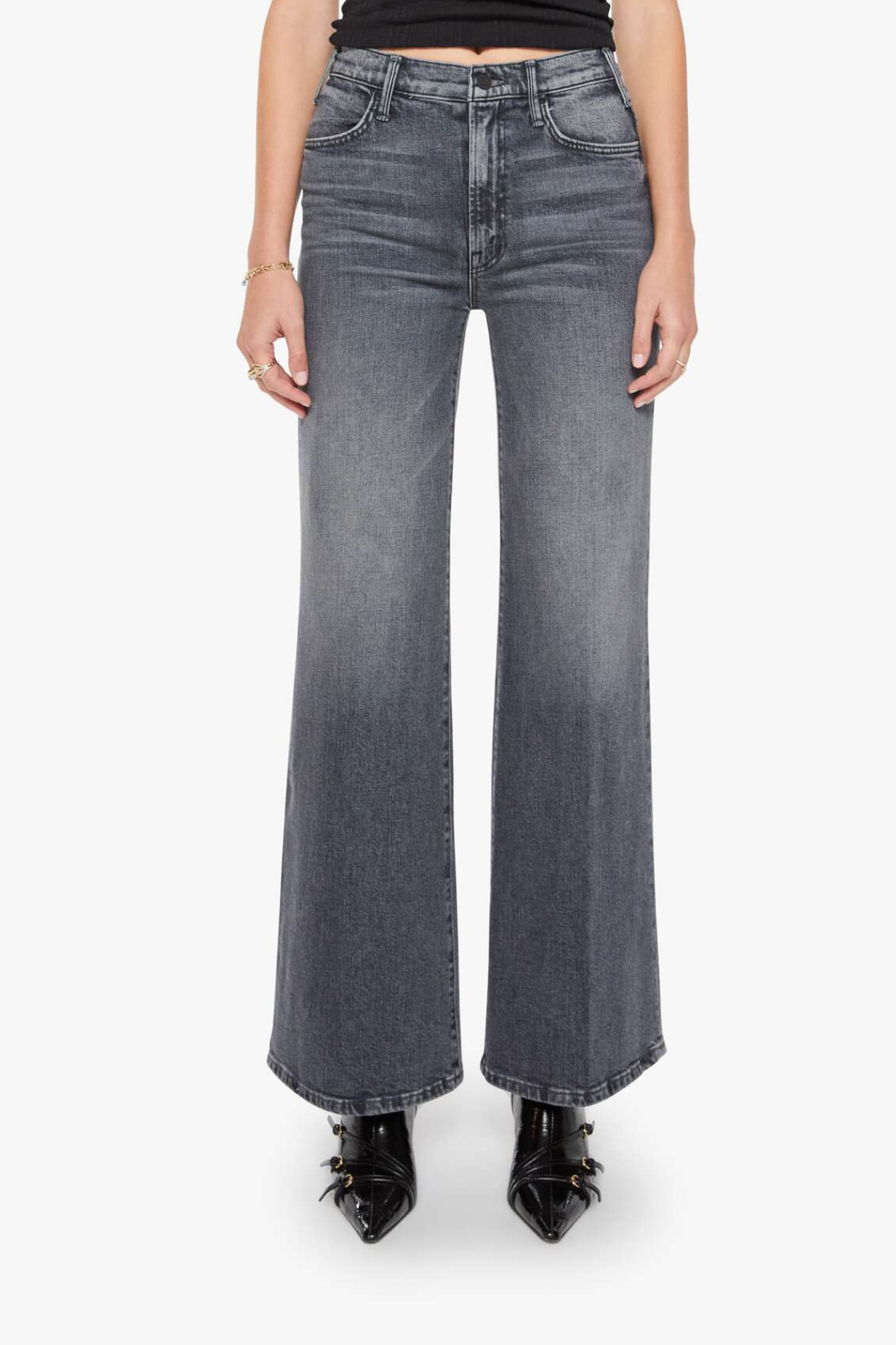 A model from the waist down wearing high-waisted, wide-leg gray denim jeans with a faded wash, paired with black pointed-toe heels against a plain white background.