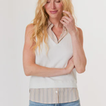 Woman wearing a sleeveless top with a striped pattern over a button-up shirt, paired with jeans on a white background.