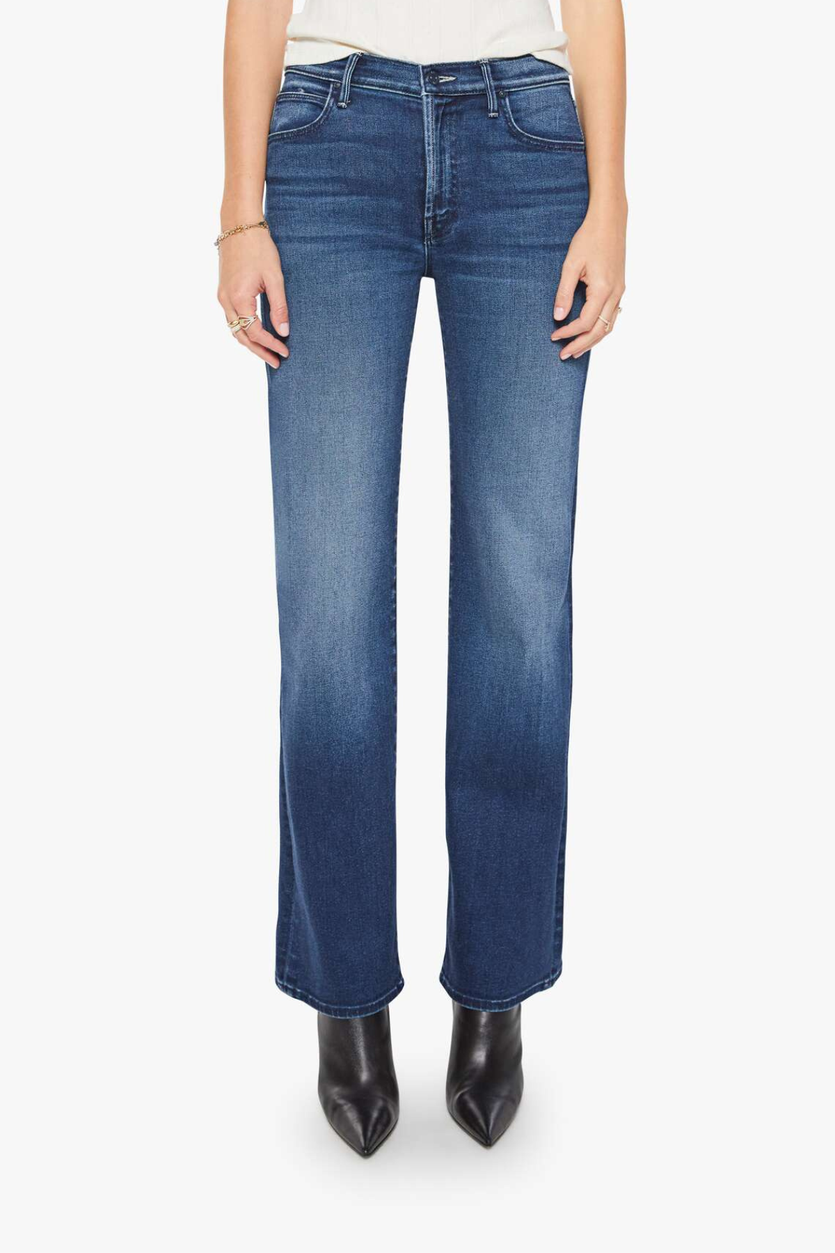 A model from the waist down wearing medium wash blue denim jeans with a straight-leg fit, paired with black pointed-toe ankle boots against a plain white studio background.