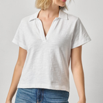 Woman wearing a white polo shirt and blue jeans on a plain background
