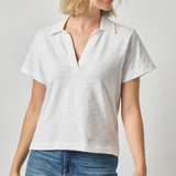 Woman wearing a white polo shirt and blue jeans on a plain background