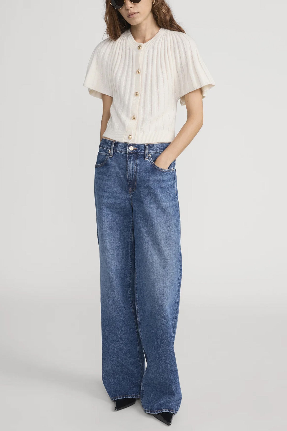 Person wearing a white blouse and blue jeans on a plain background