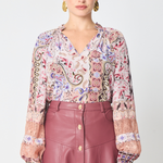 a model wearing a paisley printed long sleeve blouse with a burgundy skirt with buttons against a white background