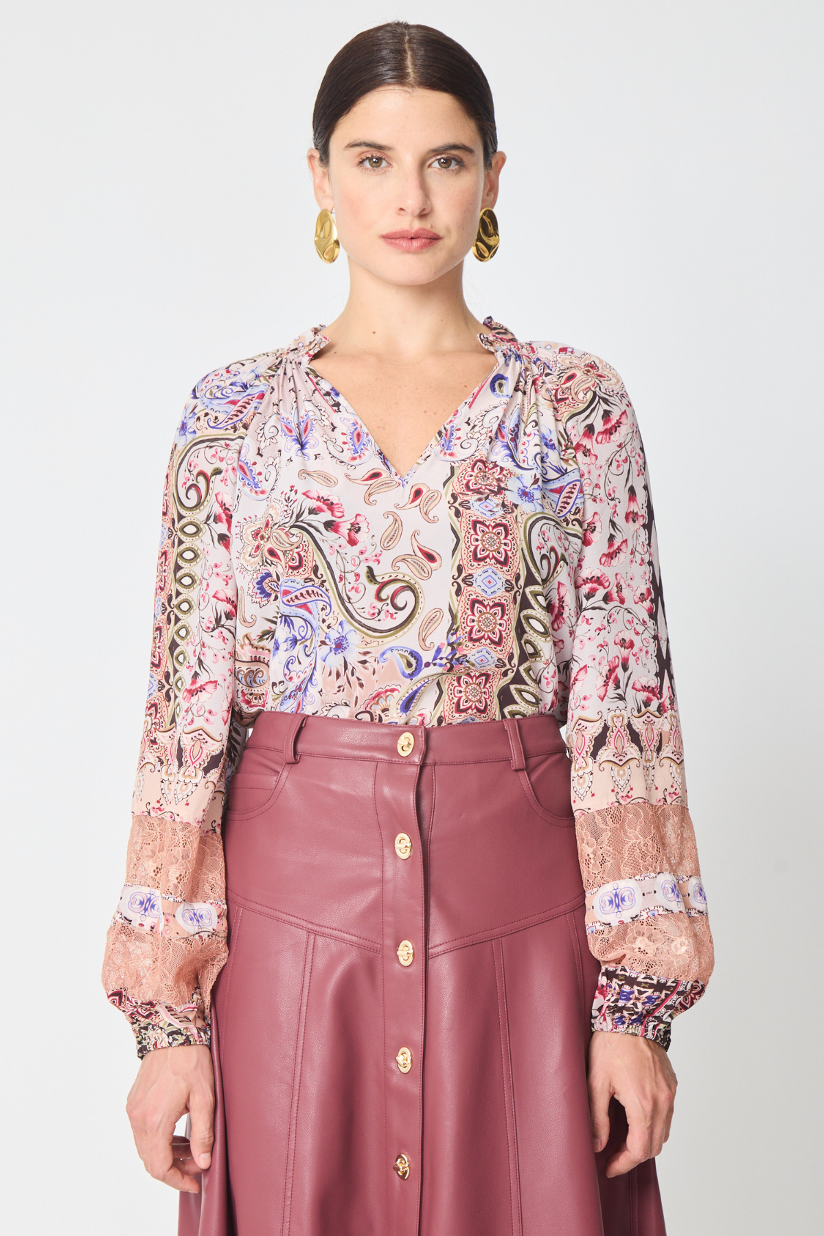a model wearing a paisley printed long sleeve blouse with a burgundy skirt with buttons against a white background