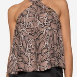 A woman wearing a halter-neck top with a brown and beige snakeskin pattern, paired with a black satin skirt, against a plain white background.