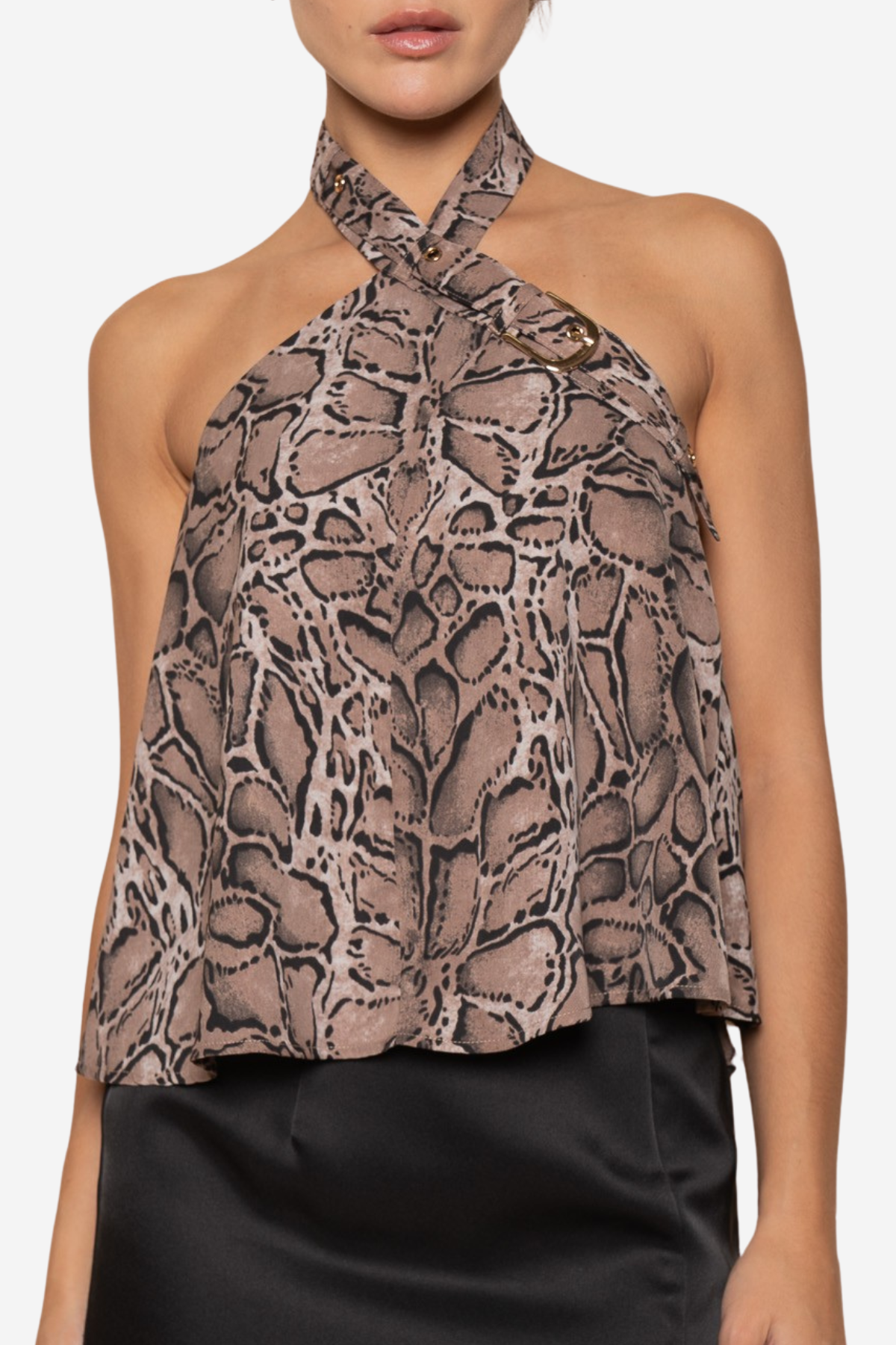 A woman wearing a halter-neck top with a brown and beige snakeskin pattern, paired with a black satin skirt, against a plain white background.